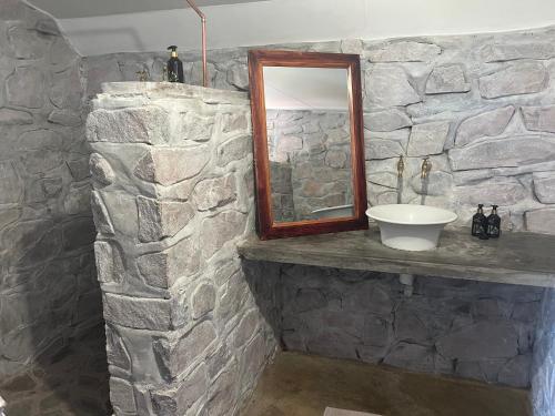 Baño de piedra con lavabo y espejo en Little Sossus Lodge, en Sesriem