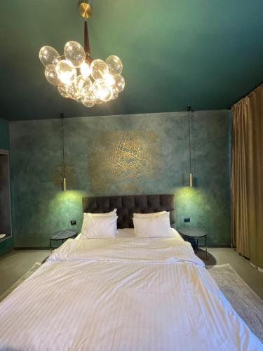 a bedroom with a large white bed with a chandelier at Pensiunea Casa Buna in Gîrbova