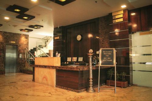 a restaurant with a counter with a clock on the wall at Hotel Tea County in Dibrugarh