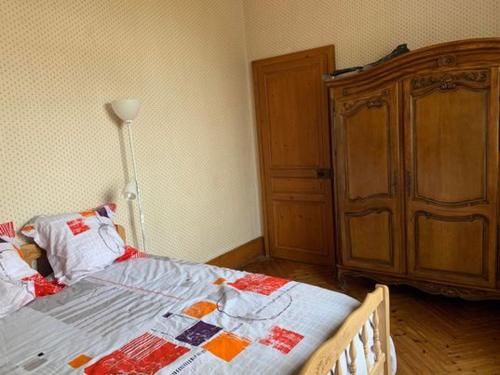 1 dormitorio con 1 cama y armario de madera en chambre chez l'habitant 2, en Biville-la-Baignarde