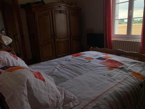 uma cama com uma colcha num quarto em chambre chez l'habitant 2 em Biville-la-Baignarde