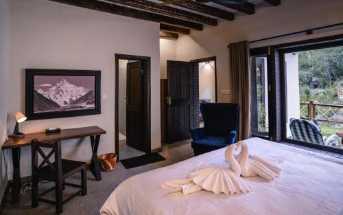 Un dormitorio con una cama y un escritorio y una ventana. en Offto Resort Hunza, en Hunza