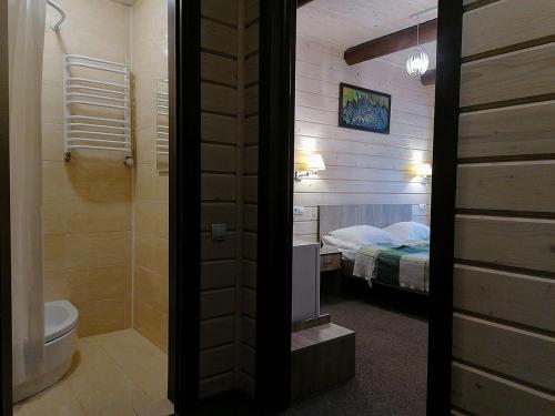 a bathroom with a toilet and a bedroom with a bed at Шале На бе́резі in Kvasy