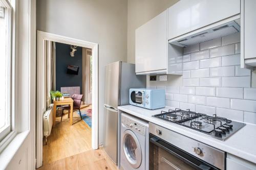 a kitchen with a stove top oven next to a dishwasher at Sunny Corner Apartment in Center of London (1) in London