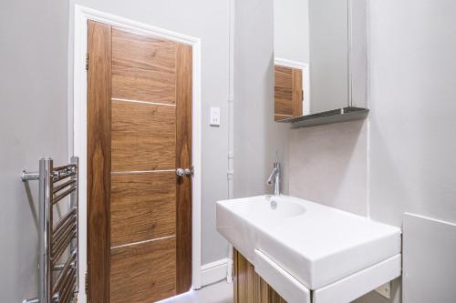 een badkamer met een wastafel en een houten deur bij Sunny Corner Apartment in Center of London (1) in Londen