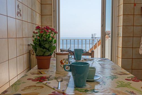 een tafel met kopjes en bloemen en een balkon bij Casa do Grifo - Incantevole appartamento con vista in Rovereto