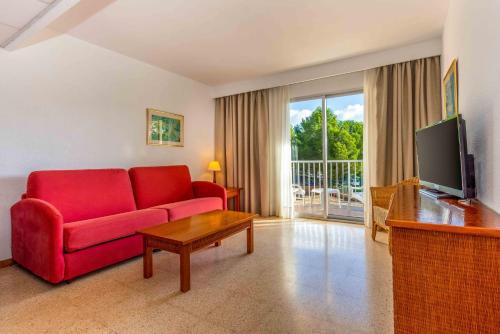 a living room with a red couch and a tv at Valentin Grand Park Suite Hotel in Paguera