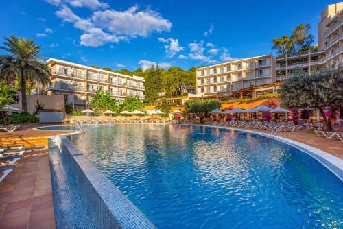 a swimming pool in a resort with tables and chairs at Valentin Grand Park Suite Hotel in Paguera