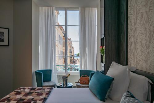 Cette chambre comprend un lit et une grande fenêtre. dans l'établissement BW Premier Collection Mondial, à Cannes