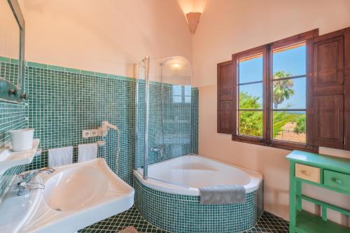 een badkamer met een bad, een douche en een wastafel bij Finca Santigor in Cala Ferrera