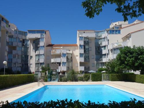 a swimming pool in front of apartment buildings at Apartment Les Caraïbes-1 by Interhome in Le Grau-du-Roi