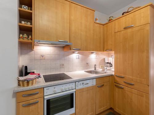 kuchnia z drewnianymi szafkami, zlewem i kuchenką w obiekcie Apartment Dachstein-3 by Interhome w mieście Flachau