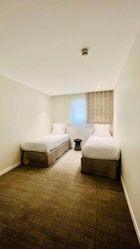 a bedroom with two beds and a window at Hotel du Pin Nice Port in Nice