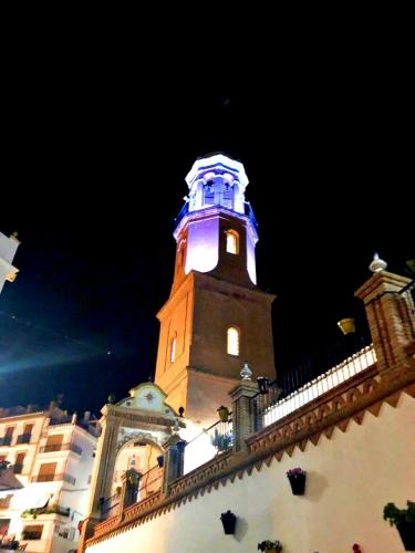 a building with a clock tower lit up at night at Casa Marlo, Spacious House in the Lively Centre of Cómpeta in Cómpeta