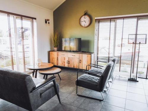 een woonkamer met een bank en stoelen en een klok bij Holiday Home De Meerparel by Interhome in Uitgeest
