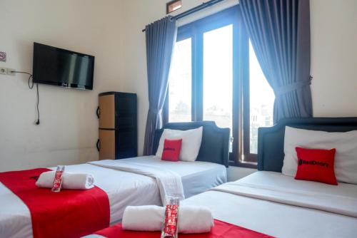 une chambre d'hôtel avec deux lits et une télévision dans l'établissement ReDdoorz At Mahameru Residence Yogyakarta, à Yogyakarta