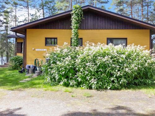 a yellow house with a bush of flowers in front of it at Holiday Home Tulisuontie a by Interhome in Ruka