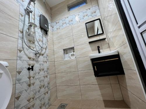 a bathroom with a shower and a sink at Tok Abu Heritage Roomstay in Pantai Cenang