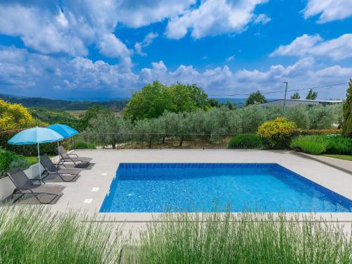a swimming pool with chairs and an umbrella at Villa Stuartma by Interhome in Donje Baredine