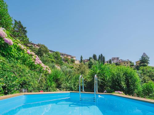 a swimming pool in front of a hill with plants at Holiday Home Il Mandarino by Interhome in Mommio