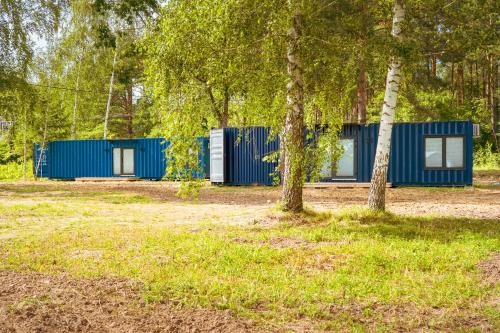two blue camping huts in a forest with trees at Arche Siedlisko Augustynka 59 in Nurzec