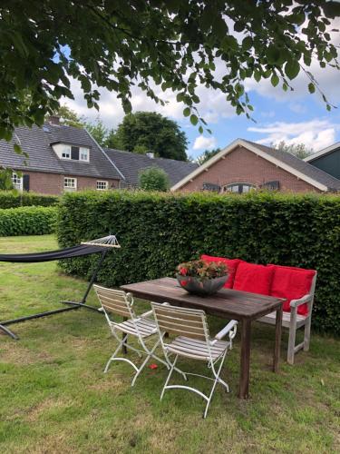 a wooden table with chairs and a bowl of flowers on it at Gastenverblijf op de Prins Hendrik Hoeve in Buren in Buren