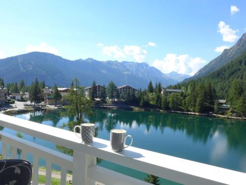 シャンペクスにあるApartment Alpes et Lac 28 by Interhomeの湖を見渡すバルコニーに座るコーヒーマグカップ2つ