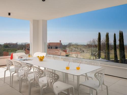 a white dining room with a white table and chairs at Villa Old Olive I by Interhome in Vodnjan