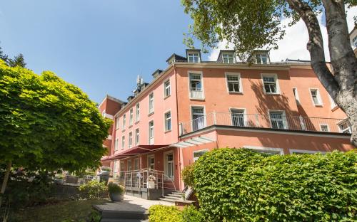 ein großes rosafarbenes Gebäude mit Bäumen davor in der Unterkunft Hotel Oranien Wiesbaden in Wiesbaden