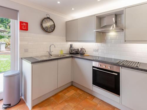 een keuken met witte apparatuur en een klok aan de muur bij Holiday Home Sea Echo by Interhome in St Austell