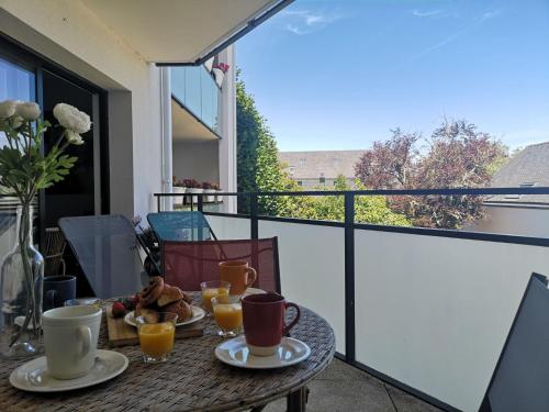 une table avec des tasses et des assiettes de nourriture sur un balcon dans l'établissement Apartment Stella Marine-2 by Interhome, à Carnac