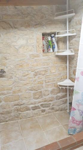 a bathroom with a stone wall with shelves on the wall at Chocolate Box Cottage in Parzac