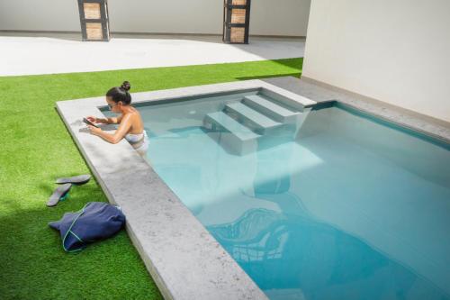 una mujer está de pie junto a una piscina en Apartamentos BocairentHomes, disfruta en pleno centro de Bocairent, en Bocairent