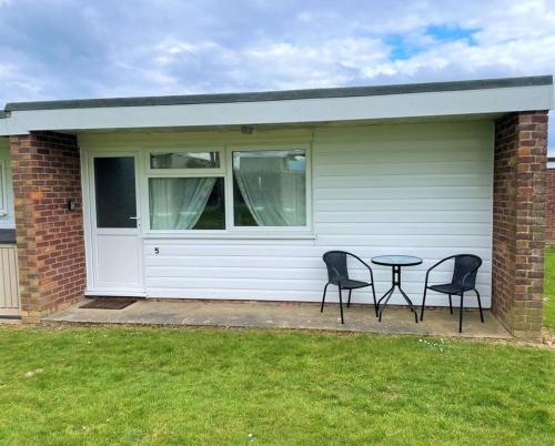 two chairs and a table in front of a garage at 5 Hemsby Holiday Chalet, Convenient for sandy beach in Hemsby