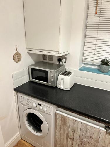 uma cozinha com um micro-ondas e uma máquina de lavar roupa no balcão em Always the same price! Free parking em Londres