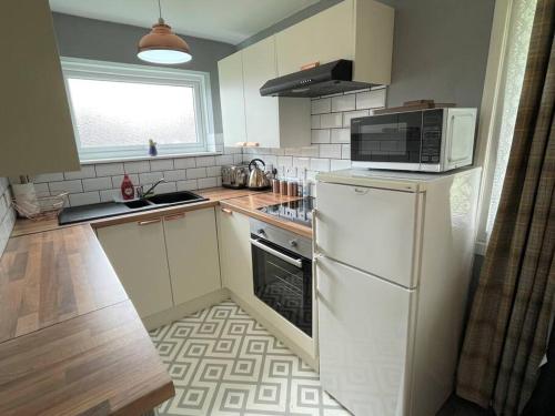 een keuken met een witte koelkast en een magnetron bij 5 Hemsby Holiday Chalet, Convenient for sandy beach in Hemsby