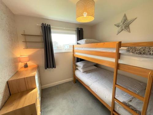 een slaapkamer met 2 stapelbedden en een raam bij 5 Hemsby Holiday Chalet, Convenient for sandy beach in Hemsby