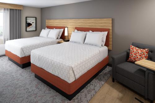 ein Hotelzimmer mit 2 Betten und einem Stuhl in der Unterkunft Candlewood Suites - Loma Linda - San Bernardino S, an IHG Hotel in Loma Linda