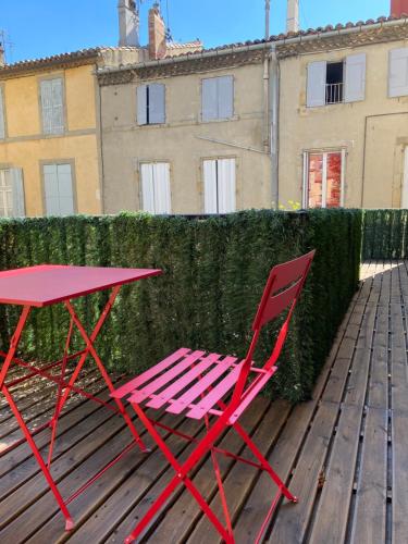 une table rouge et une chaise assise sur une terrasse en bois dans l'établissement Au cœur de Carcassonne, à Carcassonne