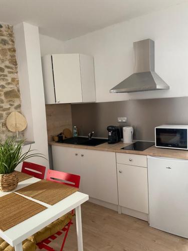 - une cuisine avec des placards blancs, une table et un évier dans l'établissement Au cœur de Carcassonne, à Carcassonne