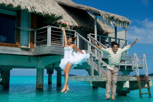a bride and groom jumping into the water on a dock at InterContinental Bora Bora & Thalasso Spa by IHG in Bora Bora