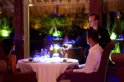 a group of people sitting around a table in a restaurant at InterContinental Bora Bora & Thalasso Spa by IHG in Bora Bora