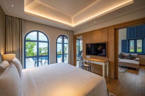 a bedroom with a large white bed and a balcony at Centara Mirage Resort Mui Ne in Mui Ne