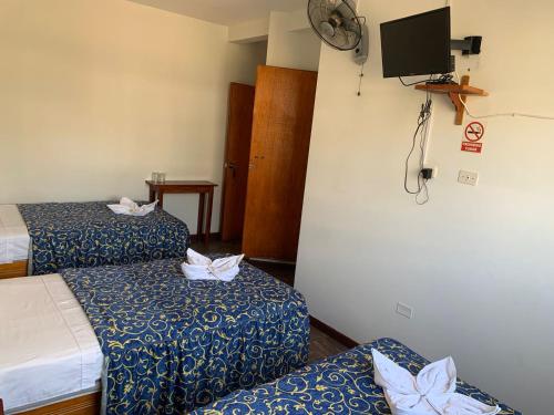 a hotel room with two beds and a flat screen tv at Hostal El Amigo in Paracas