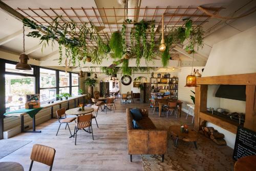 une chambre avec des tables, des chaises et des plantes au plafond dans l'établissement Sandberghe - Een plek om te verdwalen, à Uden
