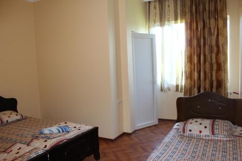 1 dormitorio con 2 camas y una ventana con cortinas en Guest House Gela en Batumi
