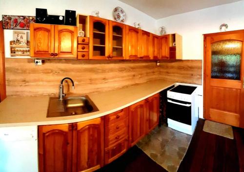 una cocina con armarios de madera y fregadero en Relax Mariánka en Betlanovce
