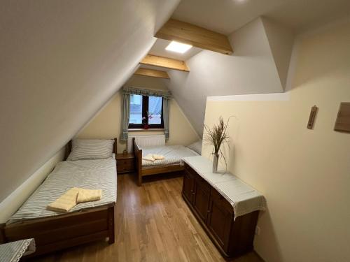 a attic bedroom with two beds and a window at Penzion Arrow in Lesná