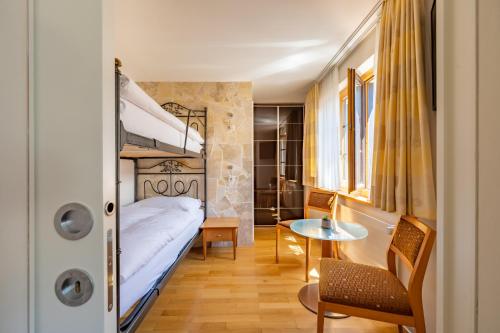 a bedroom with a bed and a desk and a table at Hotel Pollux in Zermatt