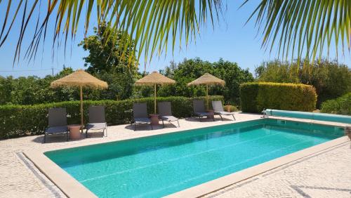 a swimming pool with chairs and umbrellas at Casa Aventura in Boliqueime